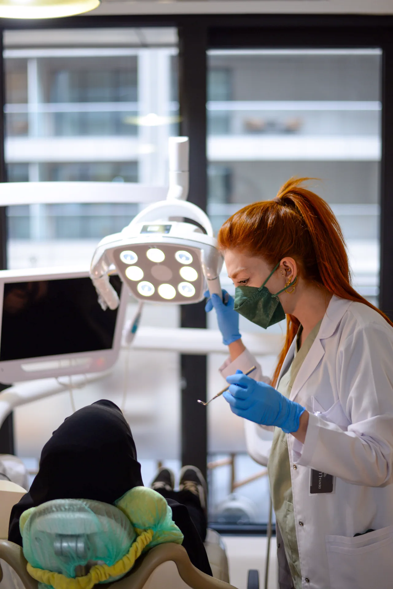 A dentist adjusting the lamp over a patient in the chair