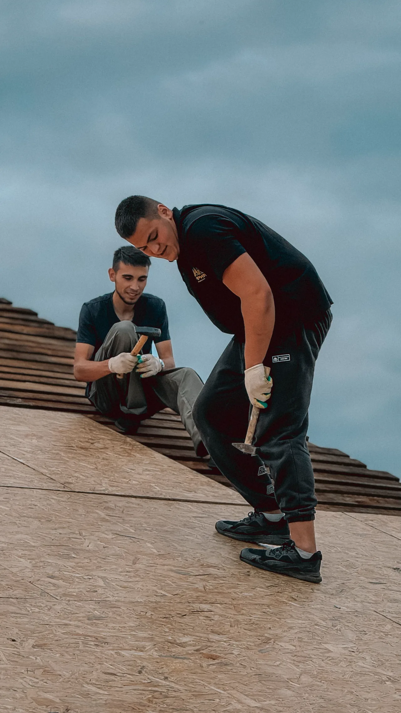 Two roofers fixing battens on a new roof deck